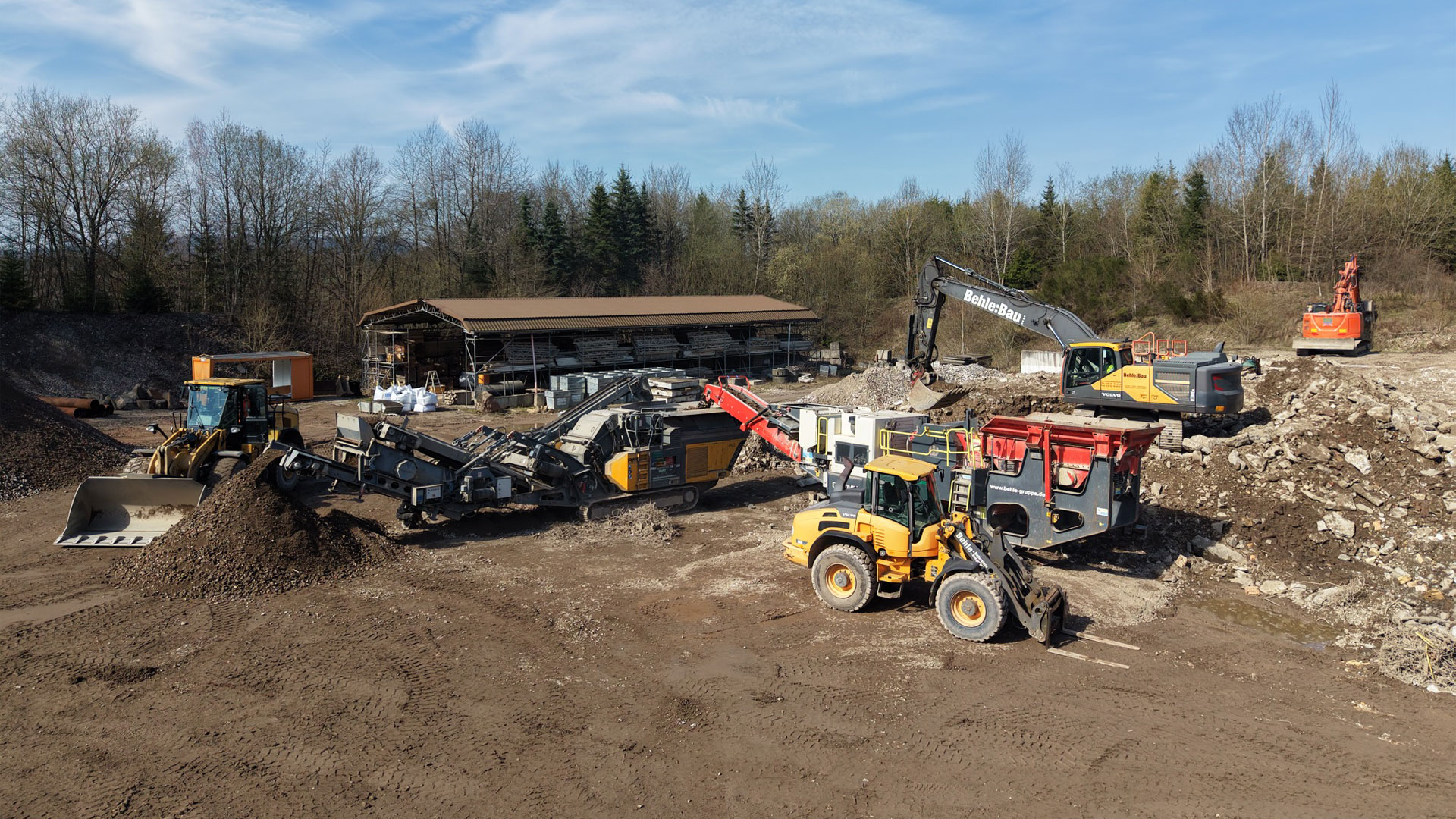 Bagger und Brecher auf dem Recyclinggelände mit aufbereiteten Schüttgütern