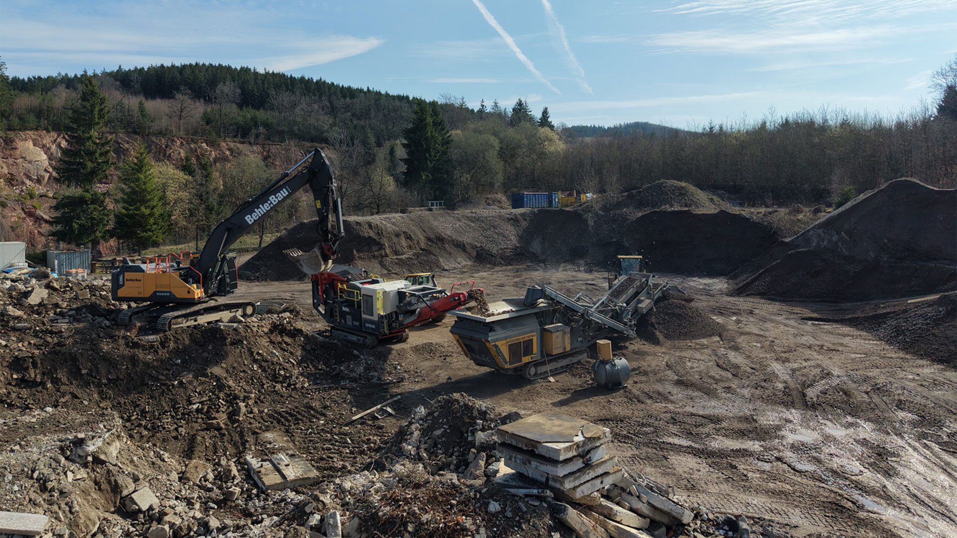 Bagger belädt Brecheranlage mit Recyclingmaterial
